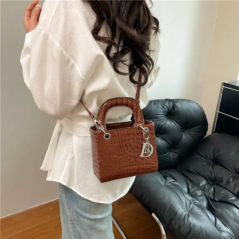 Brown crocodile leather crossbody bag worn by a woman.