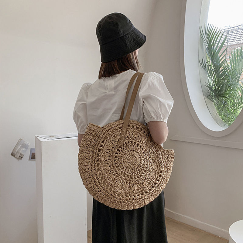 Thumbnail: Woman wearing a round handmade woven straw shoulder bag