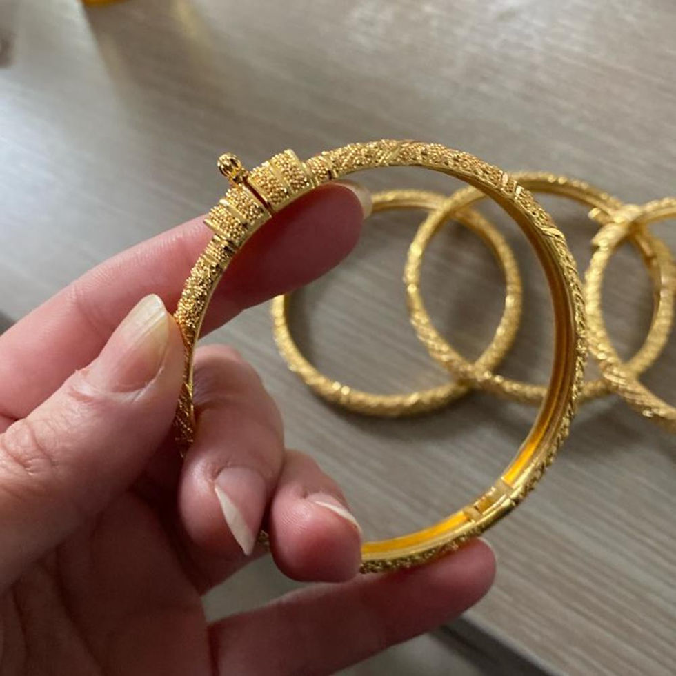 Hand holding an Ethiopian gold color bangle bracelet