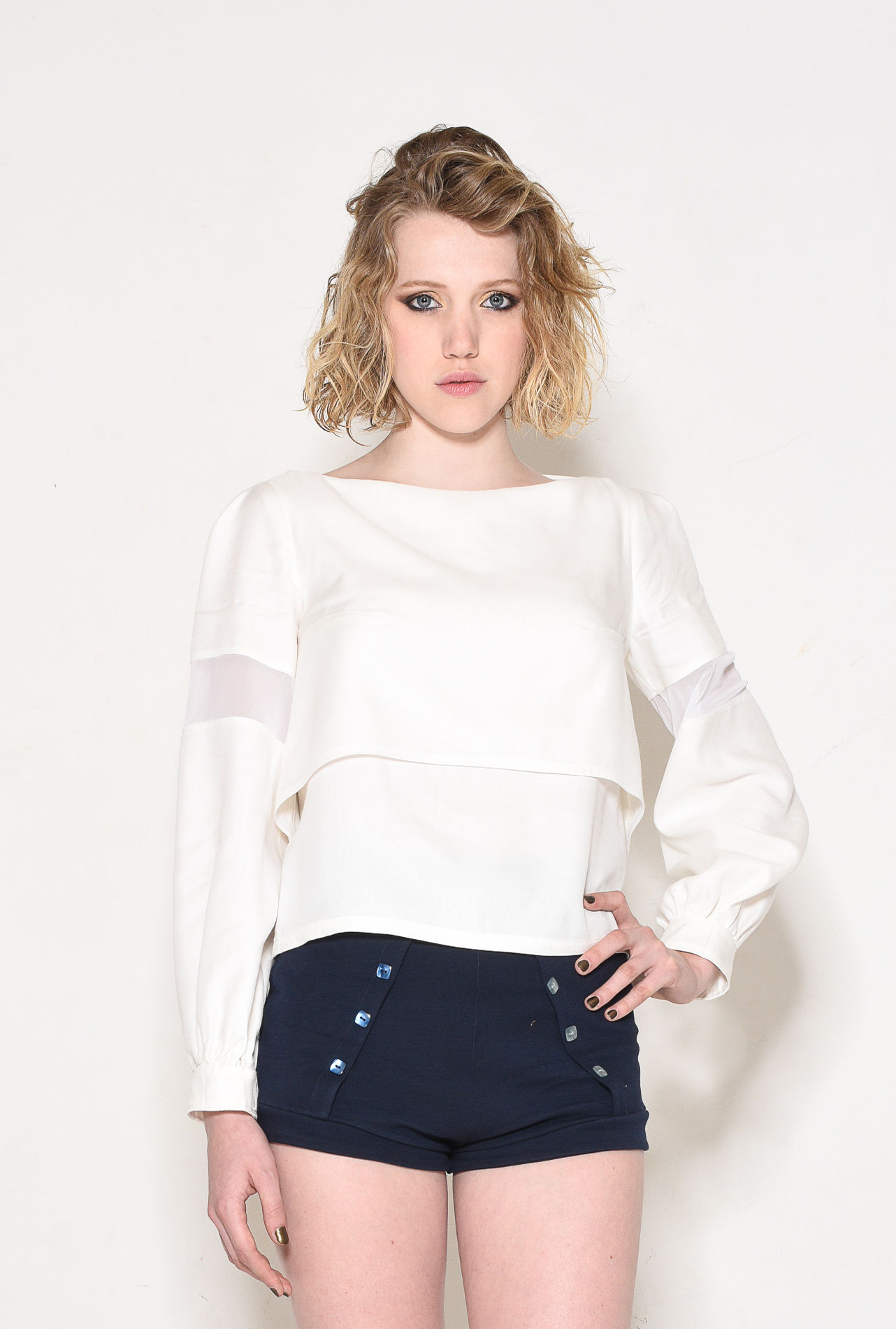 Young woman wearing white top and navy blue skirt posing Adine.