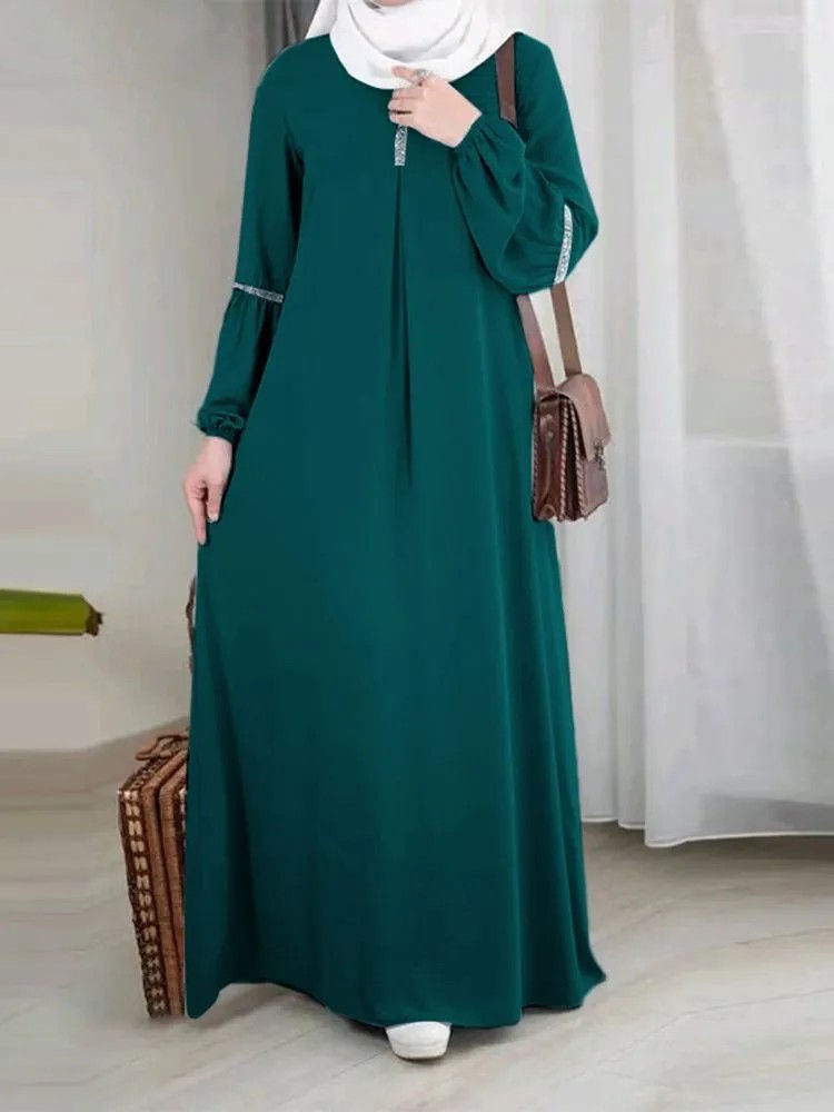 Long-sleeved dark green abaya dress with a small brown bag