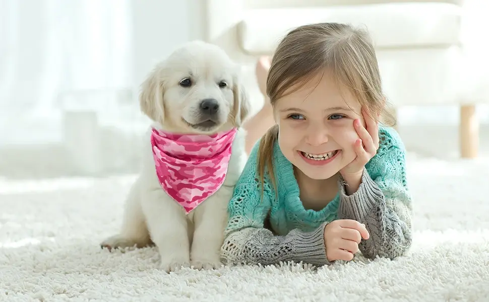 Thumbnail: Smiling girl laying next to a puppy wearing a pink bandana