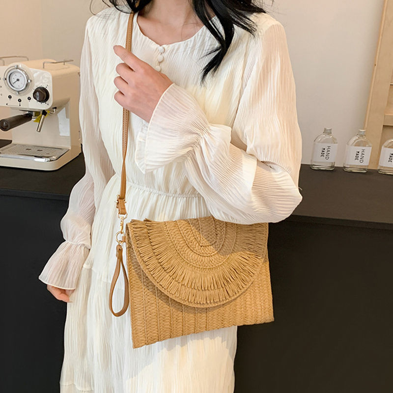 Thumbnail: Woman wearing a straw handmade weave clutch bag.