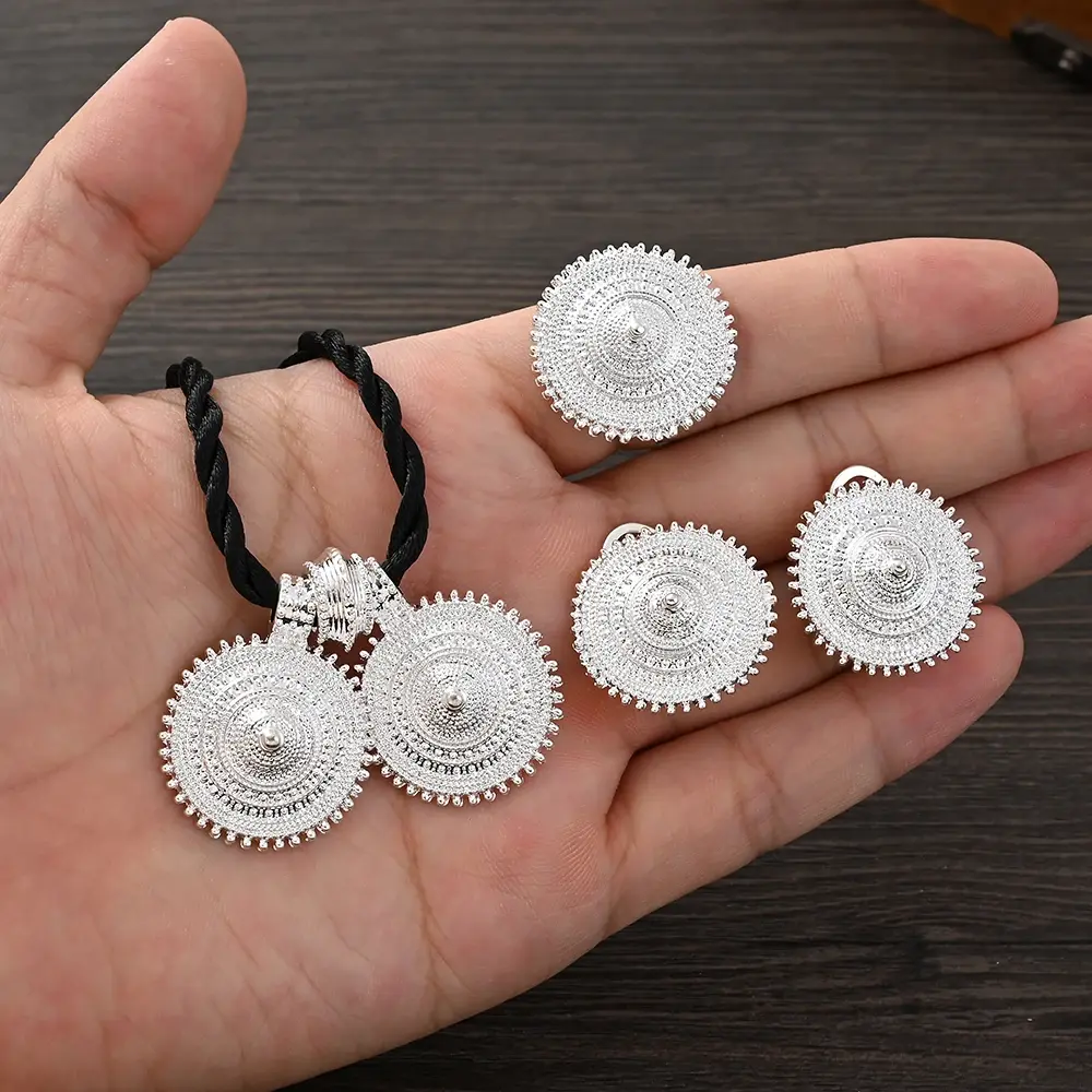 Hand holding silver-colored jewelry set including earrings, ring, and necklace, close up