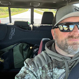 man driving in a truck with a guitar in the backseat