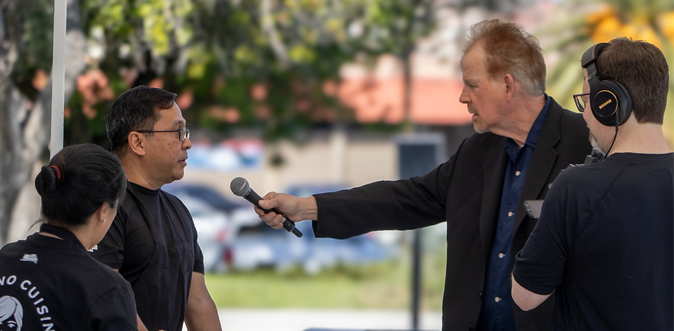 man in a suit jacket holding out a microphone to interview another man