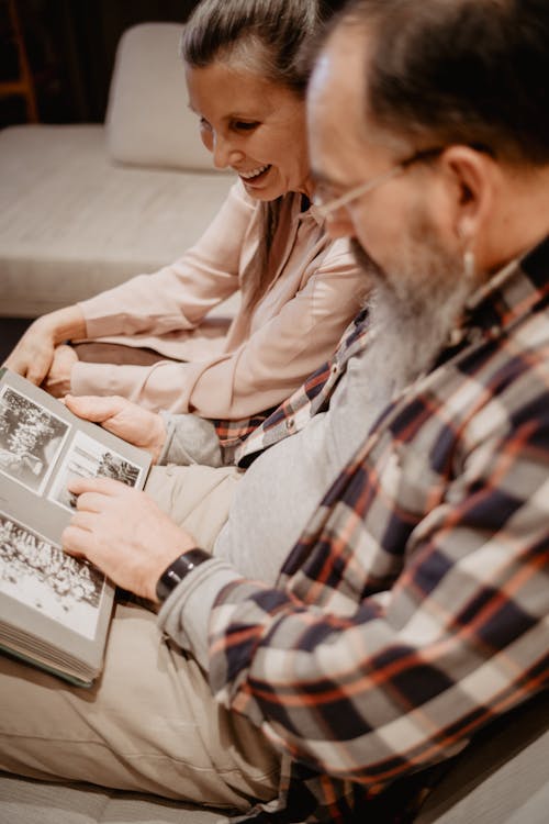 An elderly couple sitting together looking through a photo album — present, connected, at home.