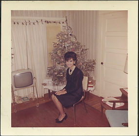 Woman poses for Christmas photo near tree and portable TV, Circa 1962-67.