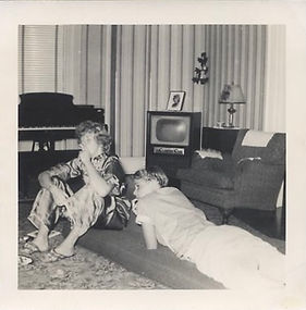 Teenage girls in pajamas smoking, lying in front of TV and piano, circa 1952-59.