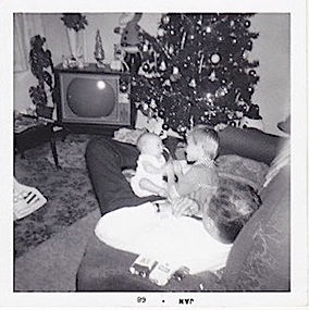 Baby and child play on father's lap during Christmas, 1968.