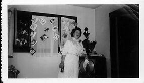 Woman in front of TV, greeting cards strung on curtains behind TV, 1955