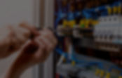 An electrician works on an electrical panel, connecting wires with tools
