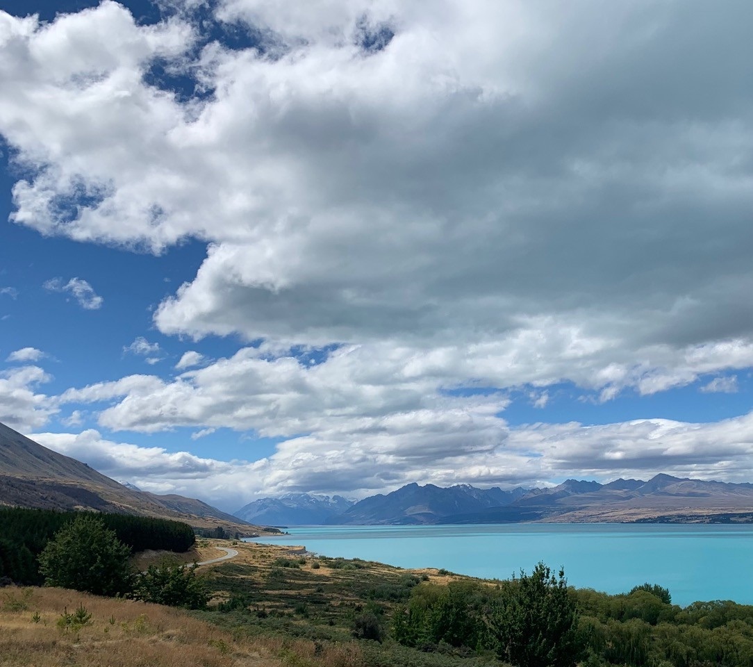 A turquoise glacial lake below broken white cloud, photographed on the road to Mt Cook in New Zealand