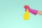 Photo of cleaning bottle with pink gloved hand.