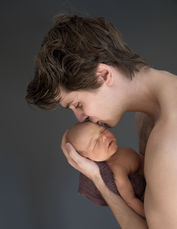Forelder kysser nyfødt baby på pannen