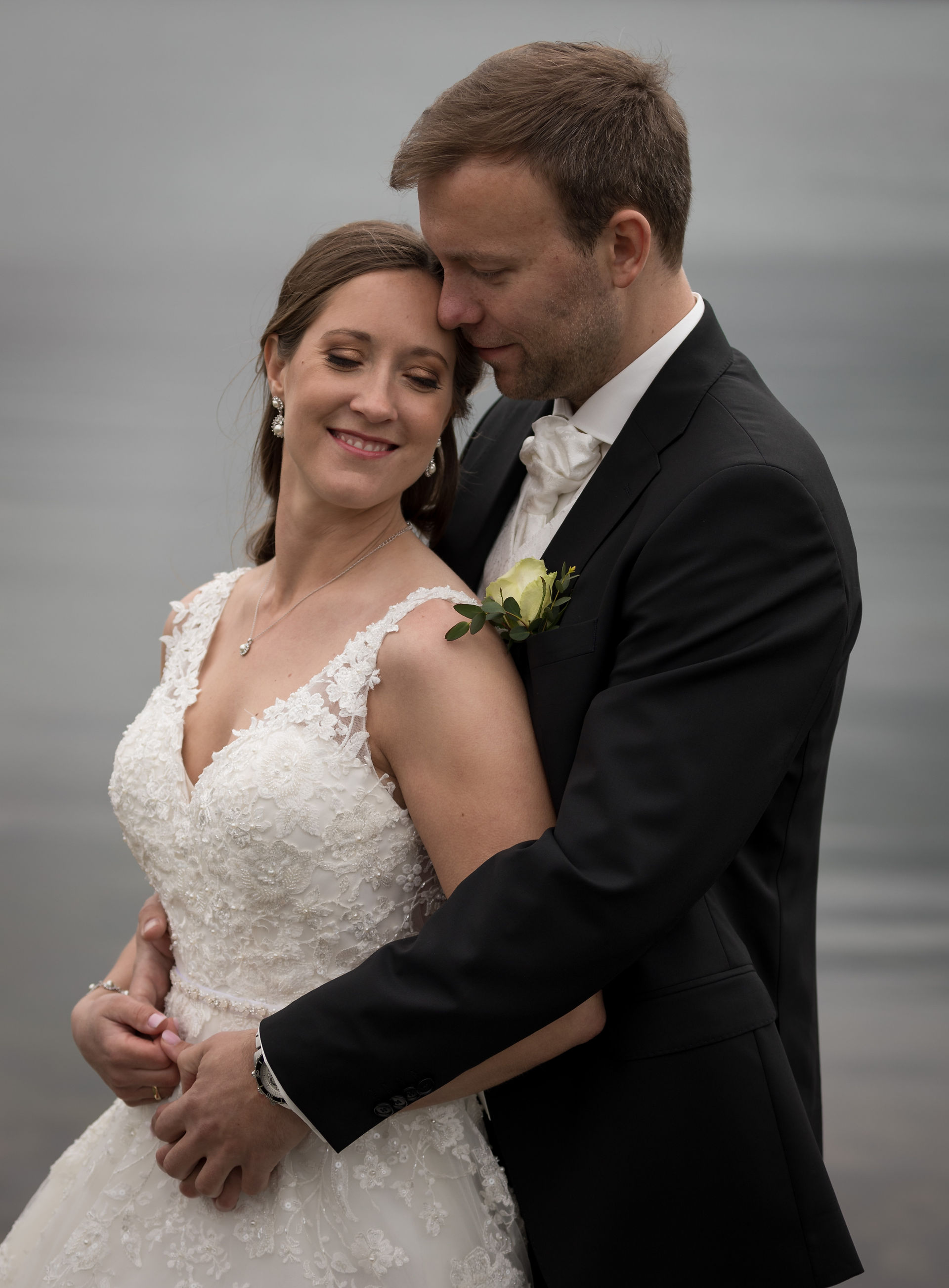 Brudepar omfavner hverandre, bruden smiler