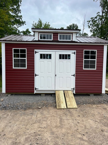 10x12 vinyl including an 8 foot roller door, dormer, barn doors with windows, and one piece ramp.