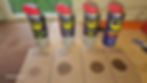 A photo of four WD-40 products sprayed on cardboard. From left to right: WD-40 Specialist Contact Cleaner, WD-40 Specialist Dry PTFE, WD-40 Specialist Silicone, and WD-40 Original