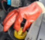 Reusable red glove removing a yellow oil cap—ideal for clean and safe car maintenance or fueling.