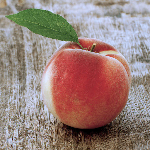 Fresh peach with a green leaf on a wooden surface
