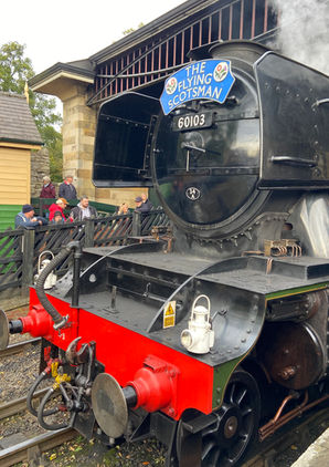 Close-up of the Flying Scotsman’s front at a Yorkshire station with people gathered nearby.