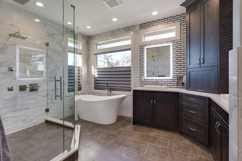 Modern master bathroom featuring freestanding soaking tub, frameless glass shower, and custom dark wood vanity