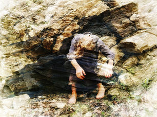 A dancer moves on a ledge of a rock formation.