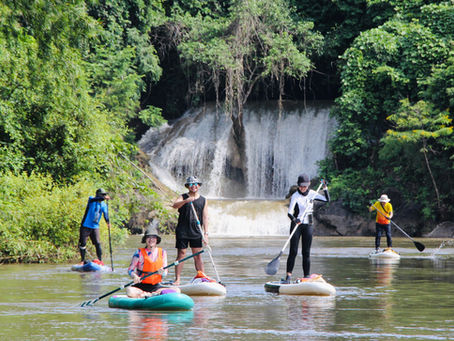 SUP boarding lesson at waterfall in Kanchanaburi Thailand with professional instructors and students learning paddleboarding techniques