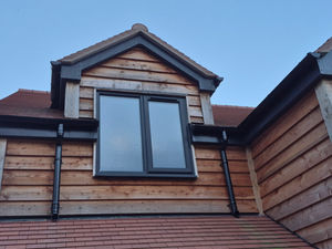 Dormer windows allow light into the first floor bedrooms. Timber cladding with grey windows and fascias creates a contemporary rural style.