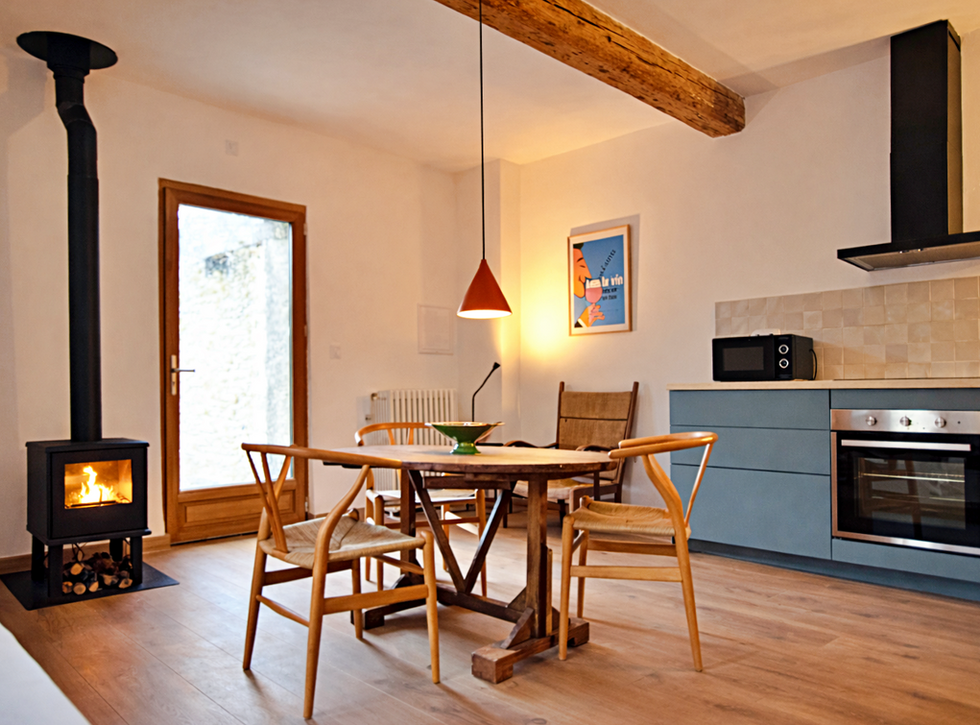 Living area and kitchen of the cottage with a view and a lit wood-burning stove, a cosy atmosphere at Domaine La Martine.