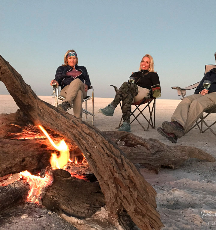 Three tourists enjoying campfire, Makgadikgadi salt pans