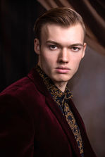 A male model poses for this dramatic headshot wearing a suit styled in the 1940's.
