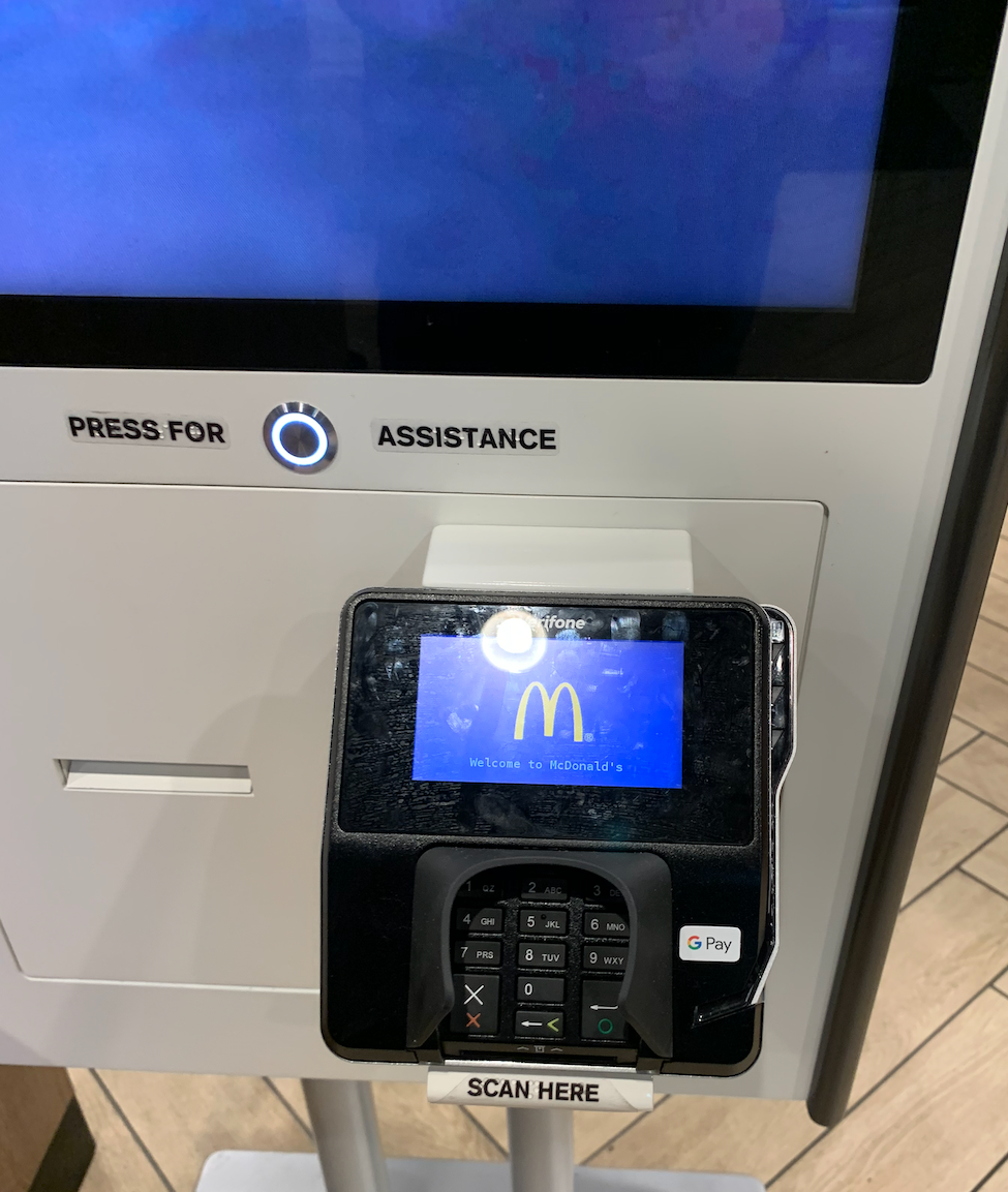 an up-close picture of the assistance button on the self ordering kiosk at McDonald's
