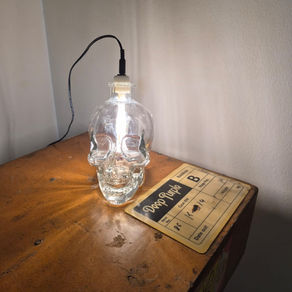Skull-shaped glass bottle converted into a bedside lamp with internal LED lighting.