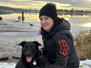Kimber sitting outdoors with her dog by the water during golden hour