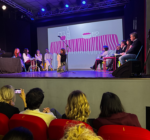 A group of people attending an event, sitting in an auditorium or theater, focused on a stage performance.