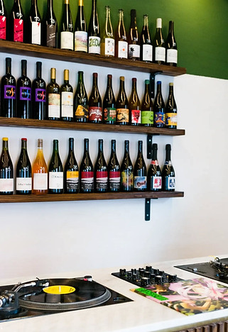 A neatly organized display of bottles on a shelf and a dj set at Ritmo Roma