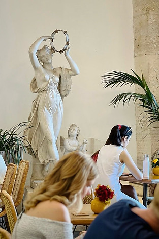 People enjoying a cultural event, gathered around a statue in an elegant venue, immersed in conversation in Rome
