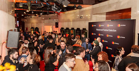 Crowd gathered at Mastercard event in Madrid, with people mingling and enjoying the atmosphere under ambient lighting.