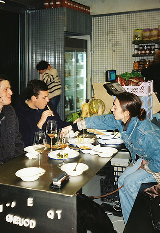 Group of people enjoying a meal together at a table, engaging in conversation and sharing food at Ritmo Roma