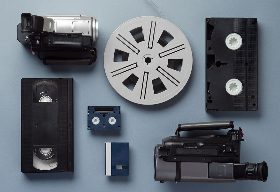 Assorted vintage camcorders and VHS, cassette, and reel-to-reel tapes arranged on a blue background, evoking nostalgia.