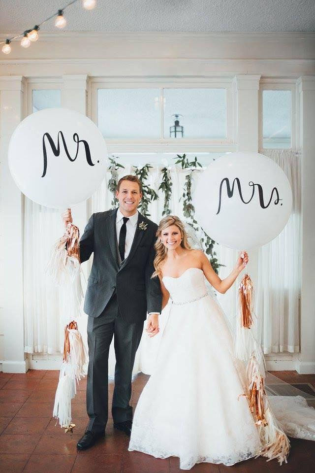 Newlyweds holding balloons with Mr. and Mrs. on their wedding day.