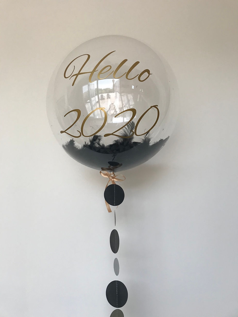 Clear balloon with "Hello 2020" text and black feathers, festive decoration