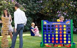 People playing games outdoors on grass; Connect 4 game visible. Party World Ferndown.