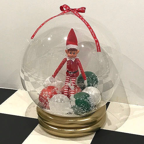 Thumbnail: Elf figurine inside a snow globe with red and green balls, festive decoration.