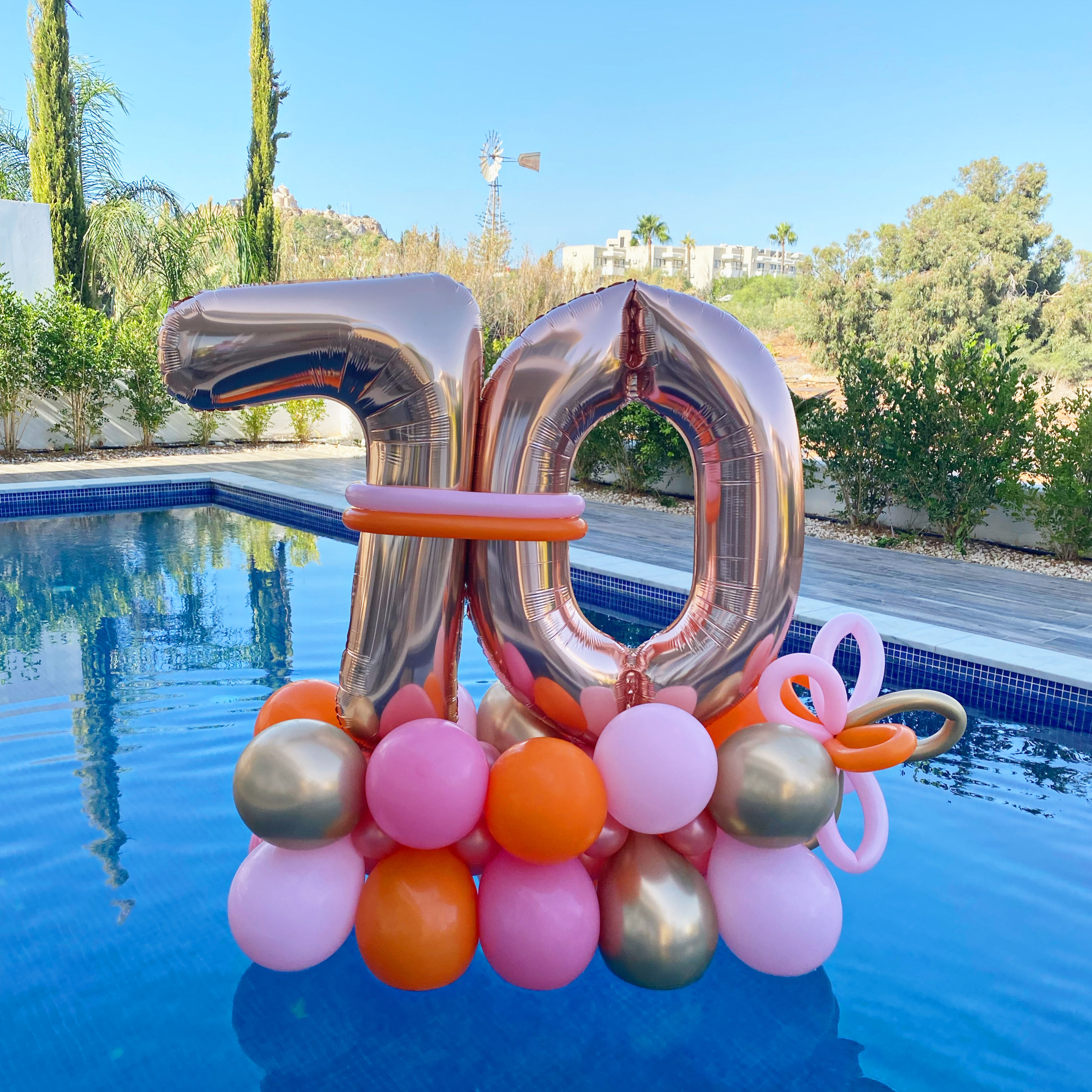 Floating balloons with number 70 celebrating a birthday by a pool