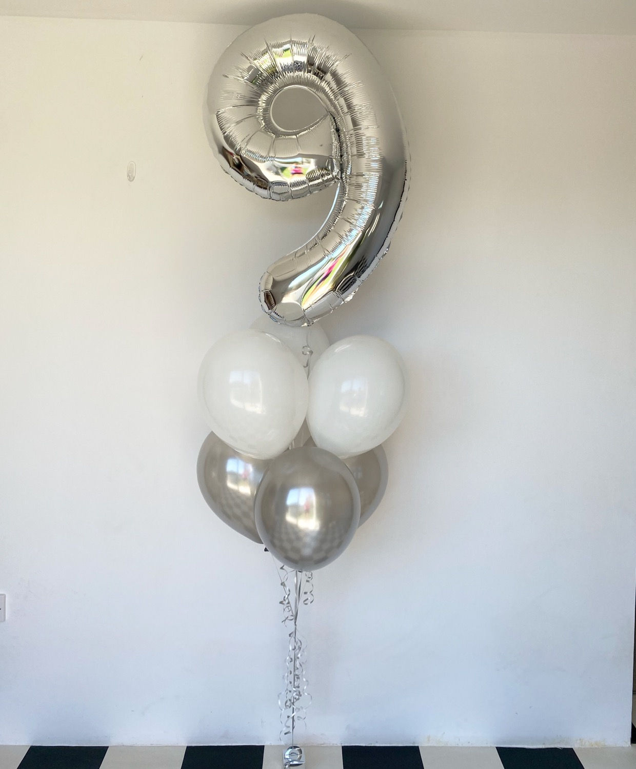 Silver number nine balloon with white and gray balloons; party decoration.