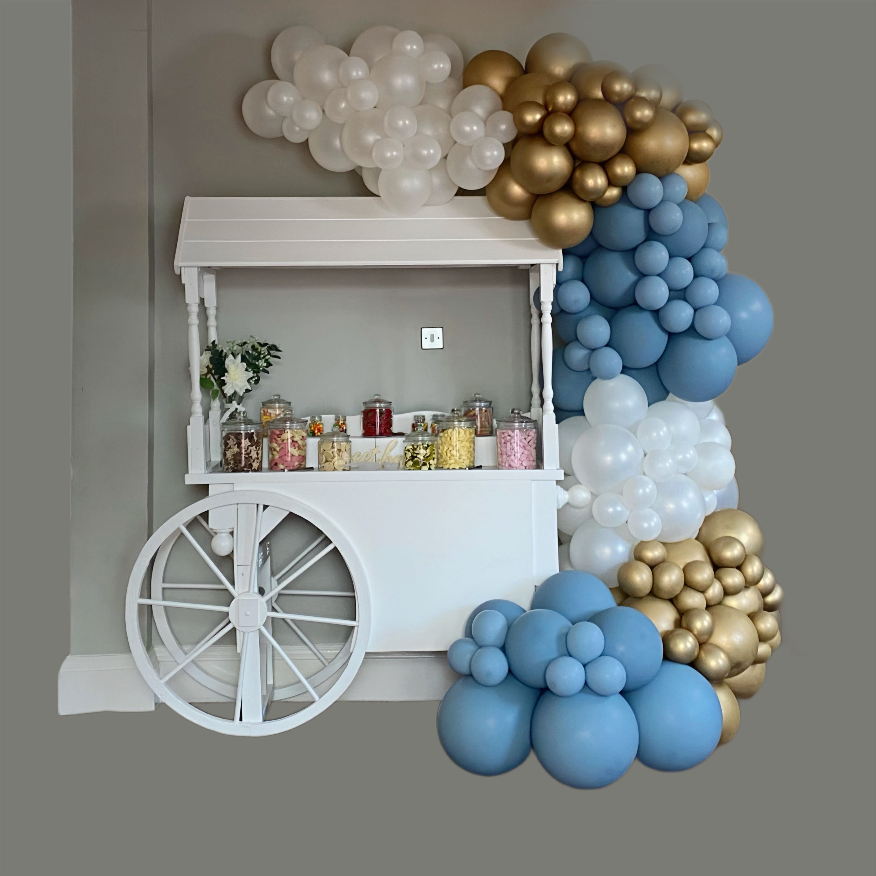 White cart with balloons and sweets display, Milestone Number Balloons & Confetti celebration setting.