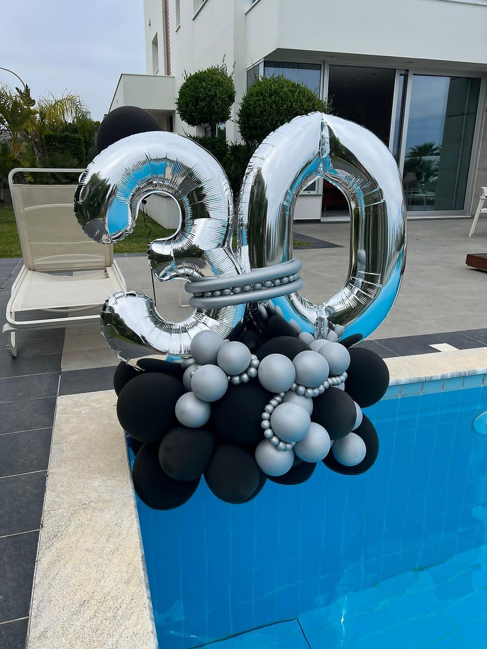 Thumbnail: Silver 30 balloon arrangement floating in pool for a birthday celebration.