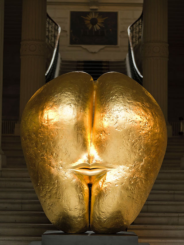 Oeuvre "Graine n'Or n°56" de Marie-Laure Viébel : graine de coco de mer dorée à la feuille d'or représentant 2 visages rassemblés par une même bouche